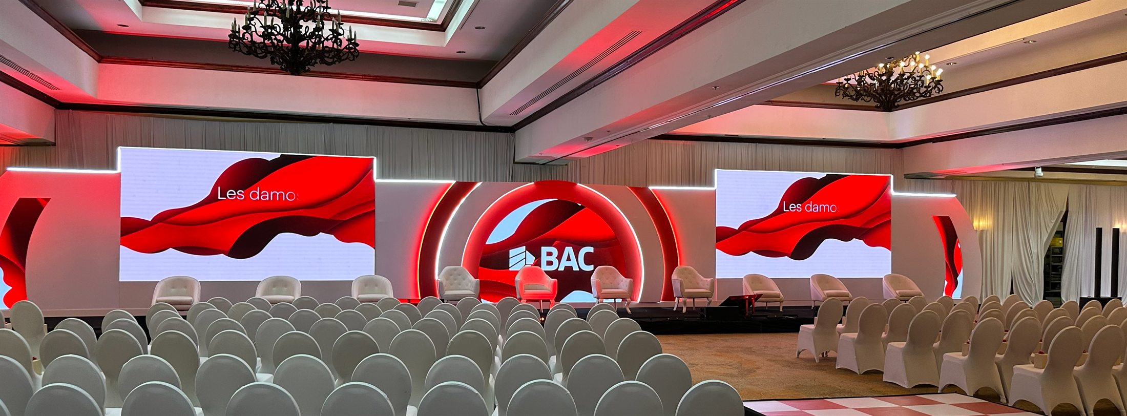 Escenografía del evento Club de Líderes de BAC con pantallas LED, sillas para audiencia e iluminación roja