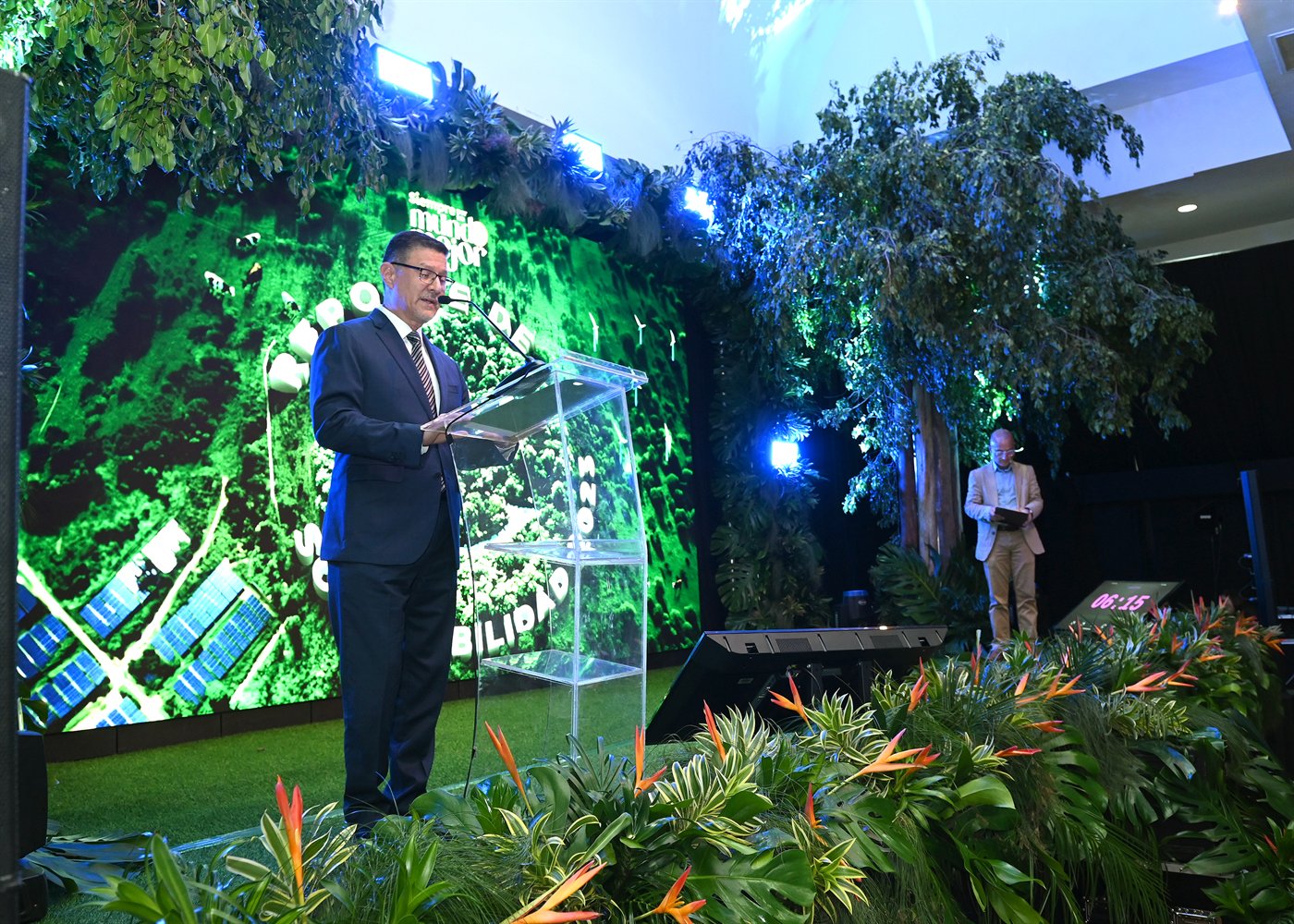 Presentación del Reporte de Sostenibilidad de Dos Pinos con vocero en podio frente a pantalla y vegetación escenográfica