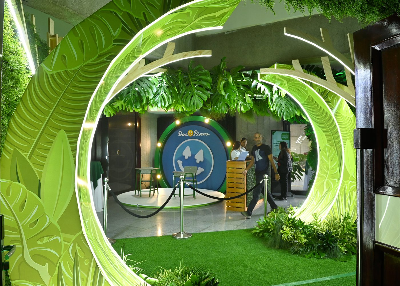 Entrada experiencial del Reporte de Sostenibilidad de Dos Pinos con arco iluminado, vegetación y espacio fotográfico